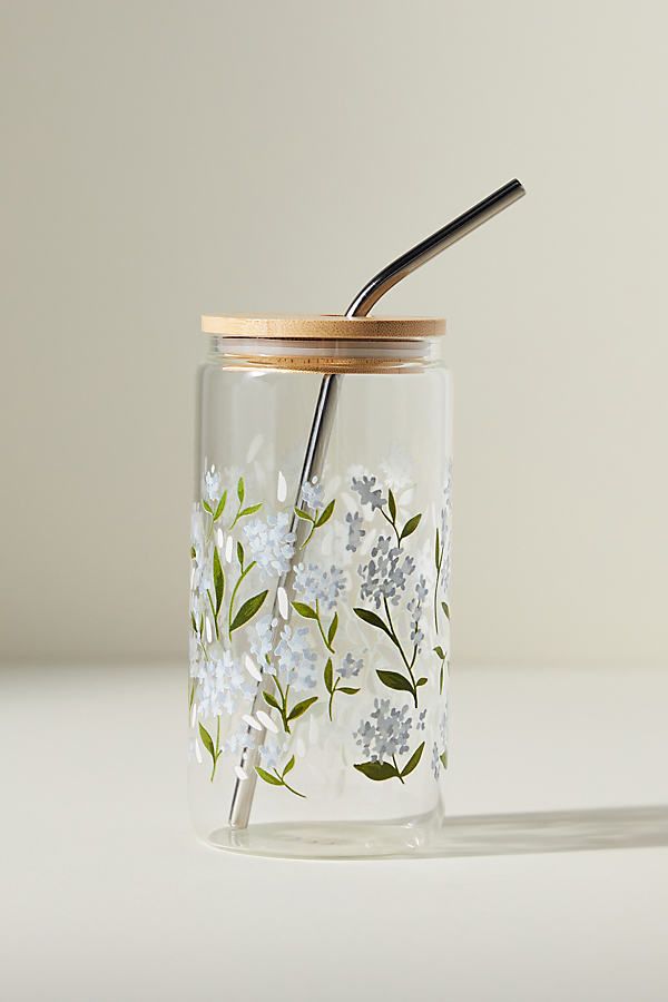 a glass jar with flowers painted on it and a straw sticking out of the lid