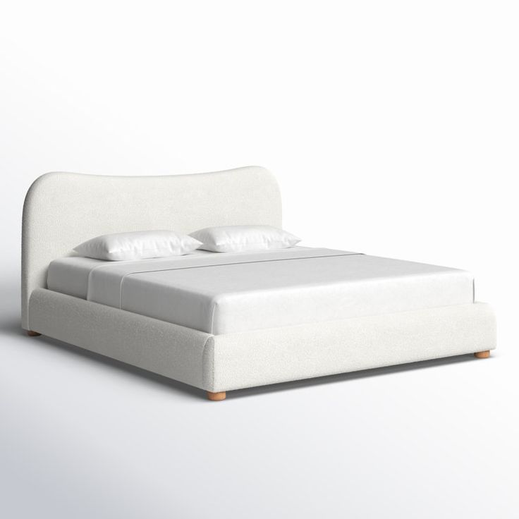 a white bed with two pillows on top of it