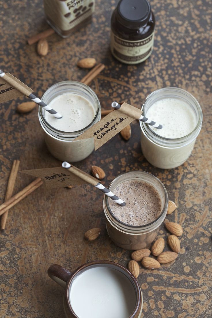 three jars filled with different types of food on top of a wooden table next to almonds