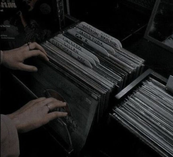 a person is reaching for records in a record player's drawer with their hands