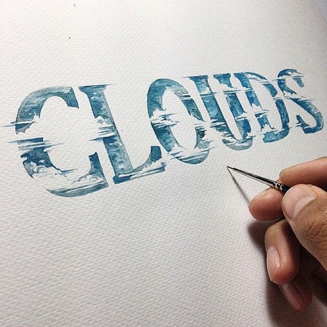 a hand is writing the word clouds on a piece of paper with some sharp scissors