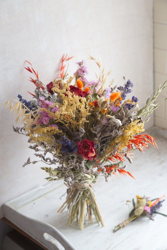 a bouquet of wild flowers sitting on top of a white table next to a window