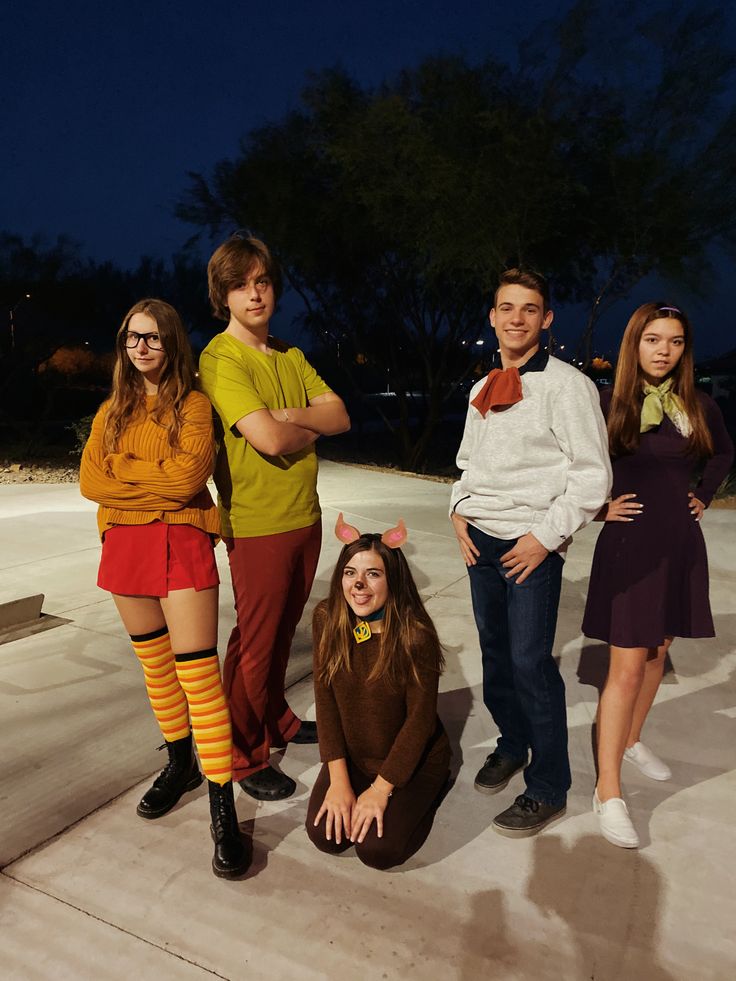 four people in costume posing for a photo together at night with their arms crossed and legs crossed