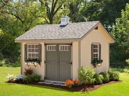 a small shed with two windows and shutters on the roof is shown in front of some trees