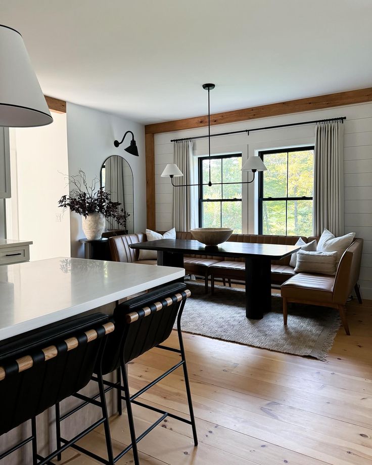 a living room filled with furniture next to a kitchen counter and dining room table in front of a large window