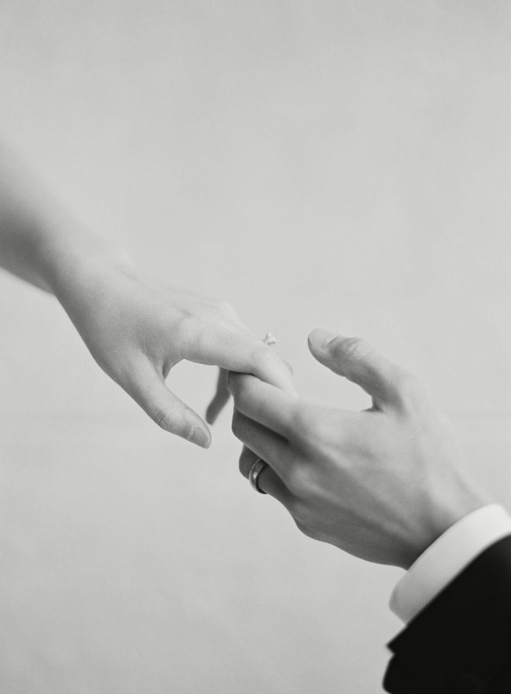 black and white photograph of two people holding each other's hands with their fingers