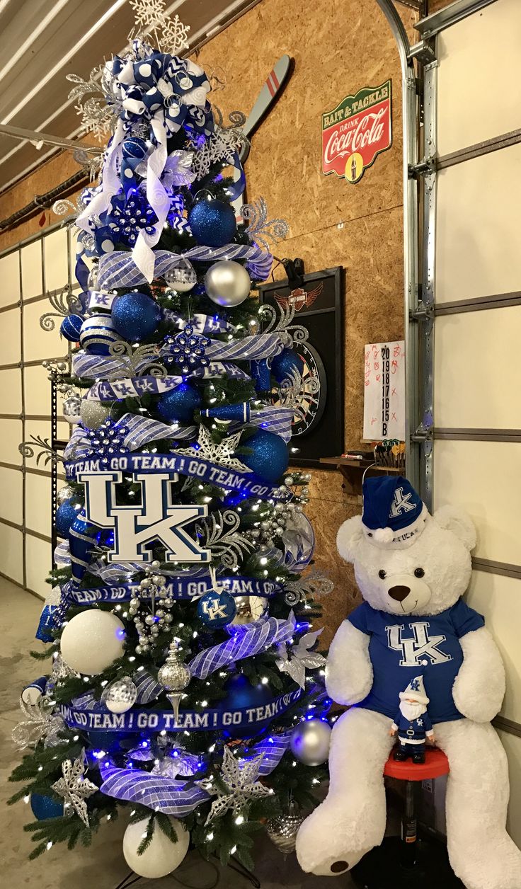 a christmas tree decorated with blue and silver ornaments is next to a white teddy bear