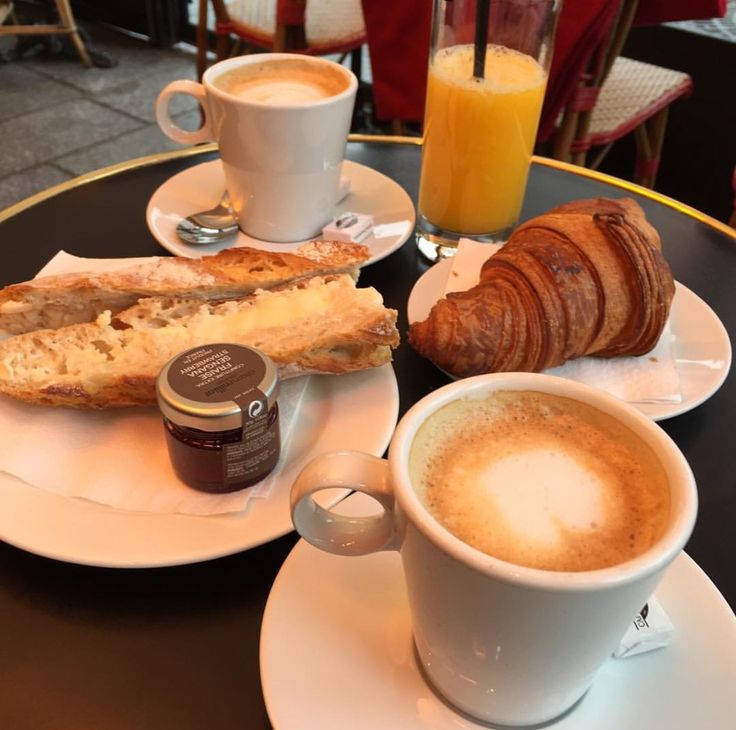 two plates with pastries, coffee and croissants sitting on a table