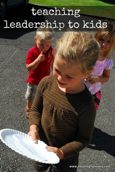 two young children are playing with paper plates in the parking lot, and one is holding a