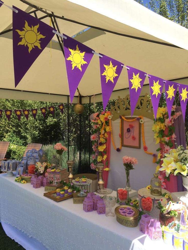 a purple and yellow party with decorations on the table under an awning in front of it