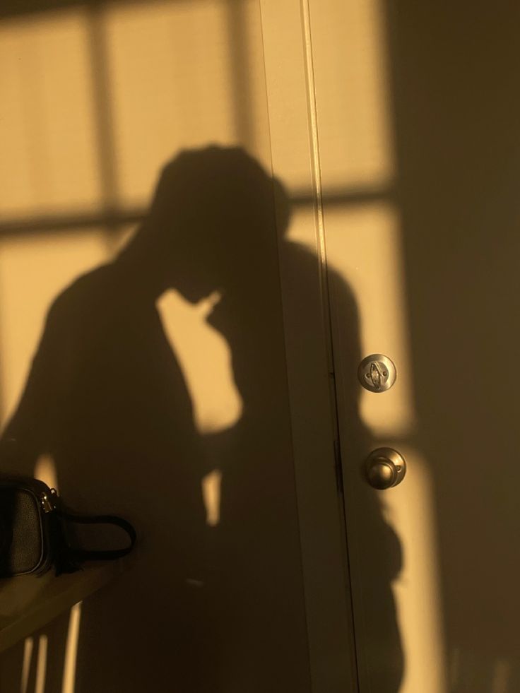 the shadow of a person standing in front of a door with their hand on his head