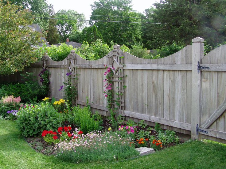 a wooden fence surrounded by flowers and greenery