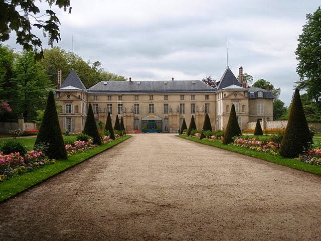 a large building with lots of trees and flowers around it