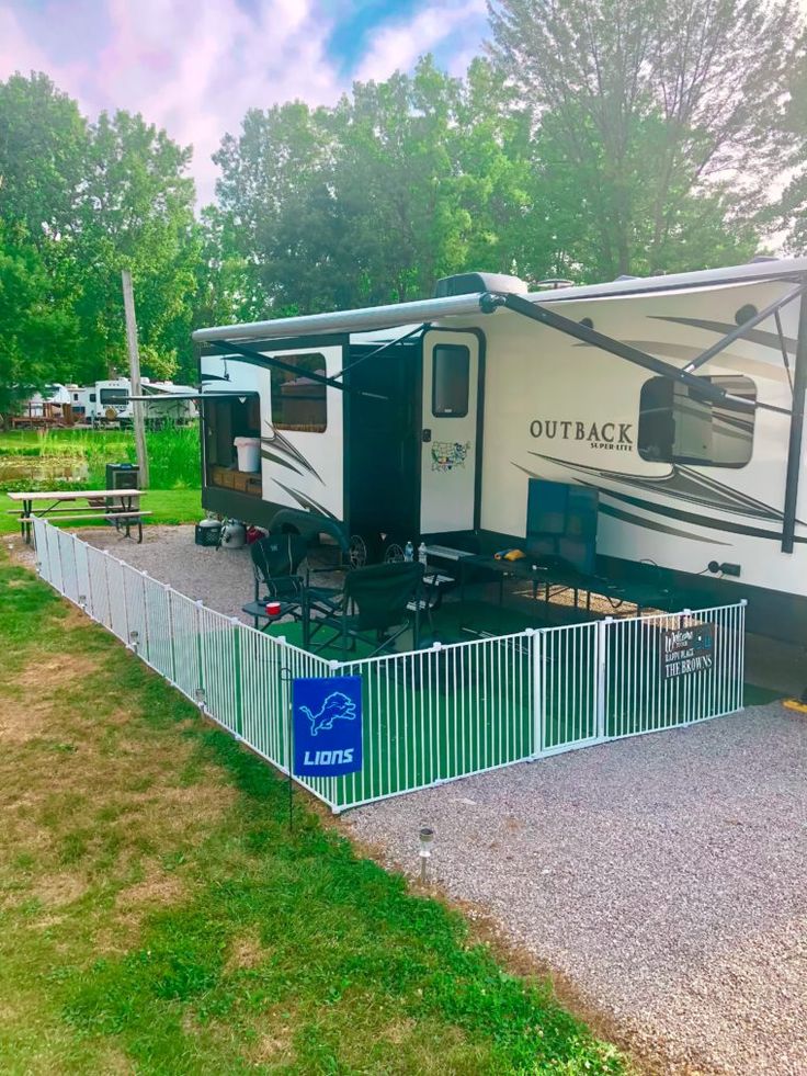 an outback trailer parked in front of a fence