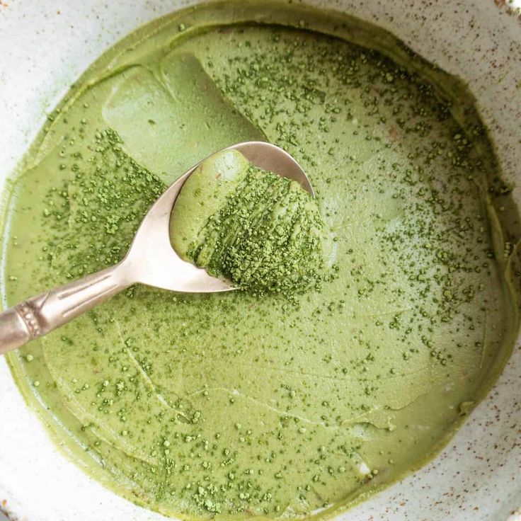 a bowl filled with green liquid and a spoon