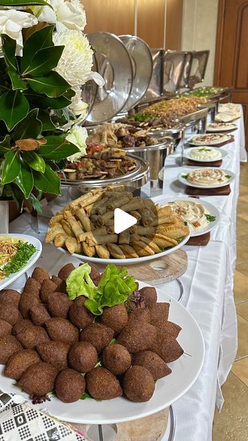 a buffet table filled with different types of food and desserts on plates, along with flowers