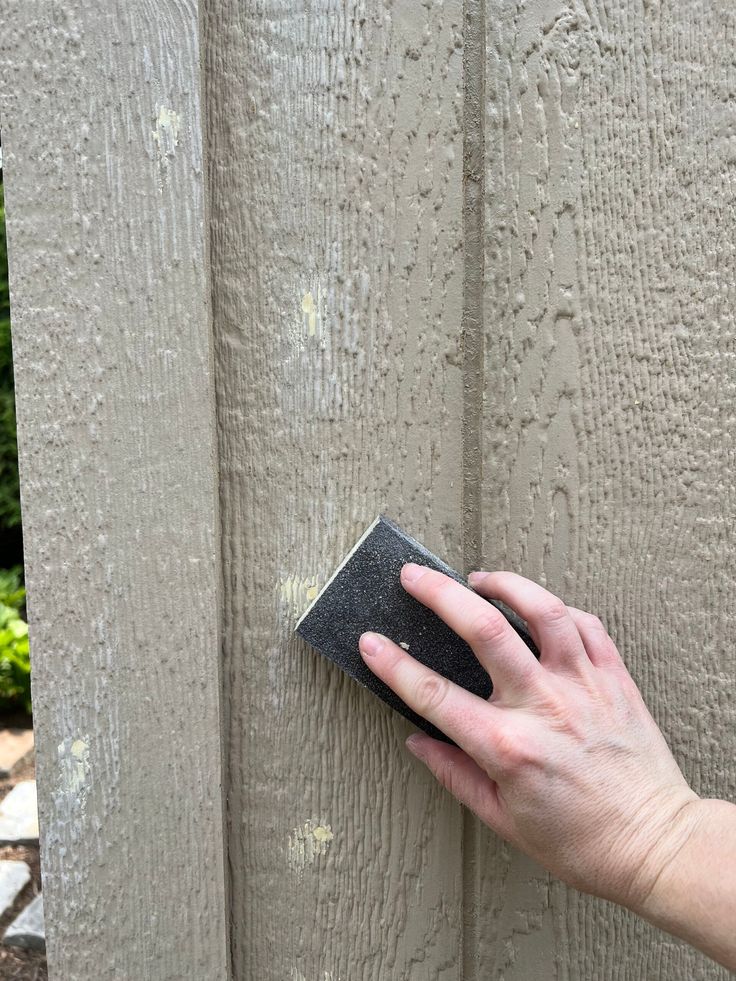 a hand is using a sponge to clean the outside of a house's siding