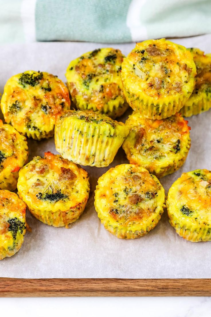 small muffins with broccoli and cheese are on a cutting board, ready to be eaten