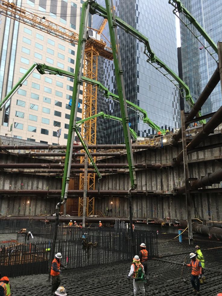 construction workers are working on the side of a large building in an industrial area with high rise buildings behind them