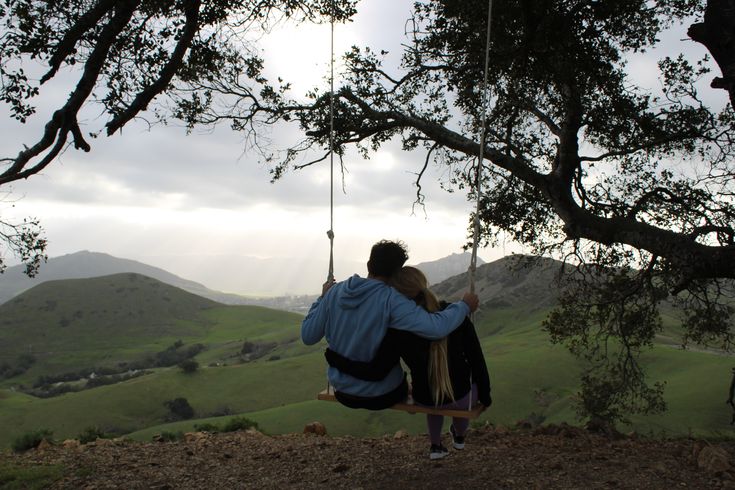 a man and woman sitting on a swing