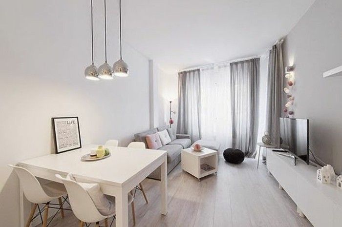 a white living room and dining area with wood flooring, light colored furniture and curtains