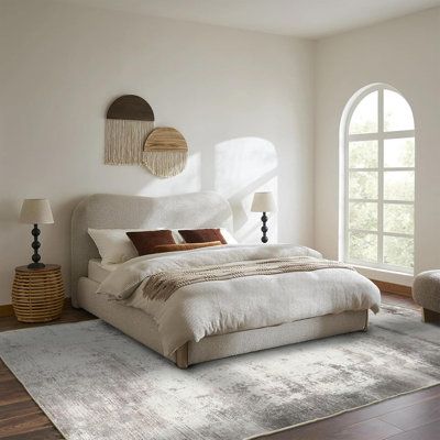 a large white bed sitting in a bedroom next to a window