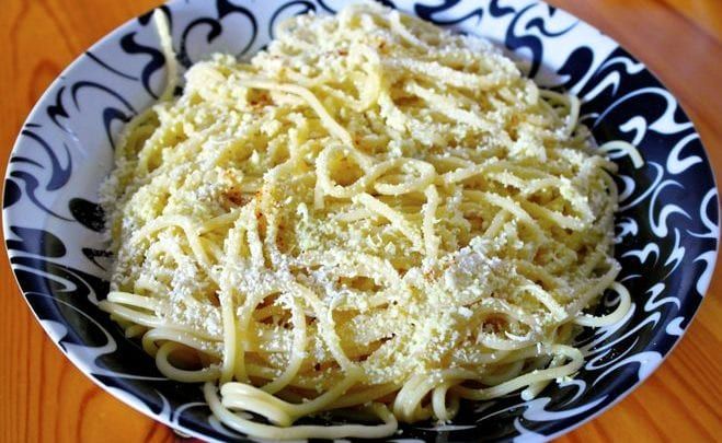 a black and white bowl filled with pasta on top of a wooden table