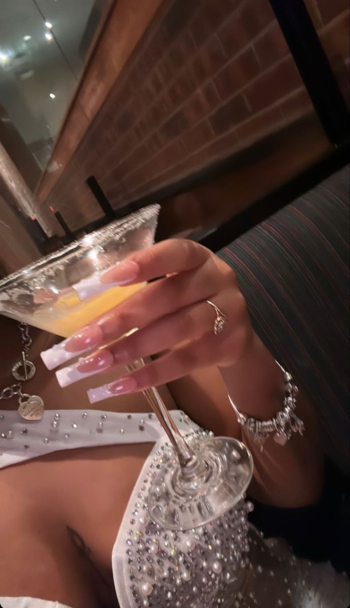 a woman holding a martini glass in her right hand and wearing jewelry on the left