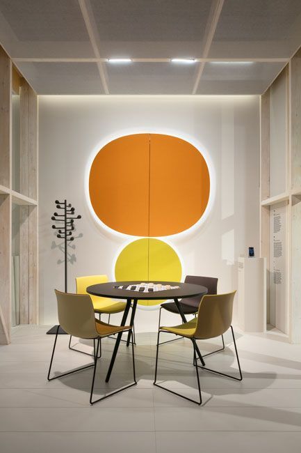 a dining table with four chairs in front of an orange and yellow circle on the wall