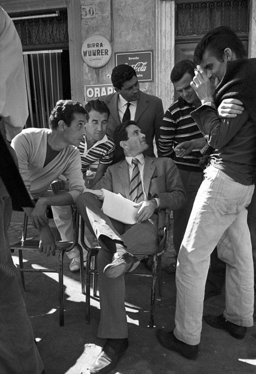 a group of men sitting around each other on chairs in front of a business building