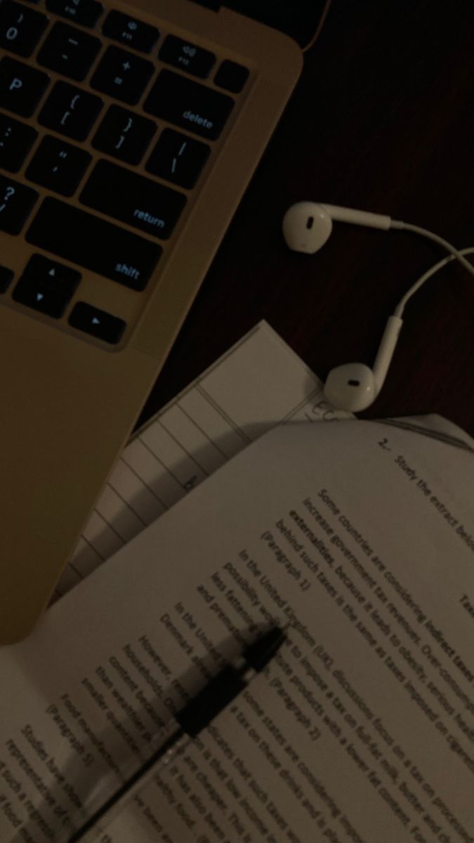 an open book with headphones on it next to a laptop