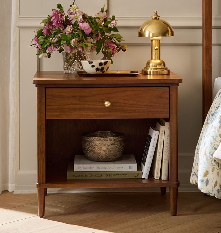 a nightstand with flowers and books on it