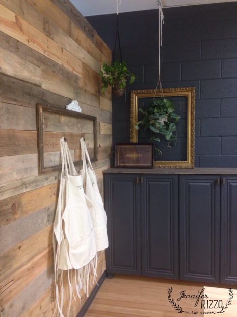 a white bag hanging on the side of a wall next to a wooden cabinet and potted plant