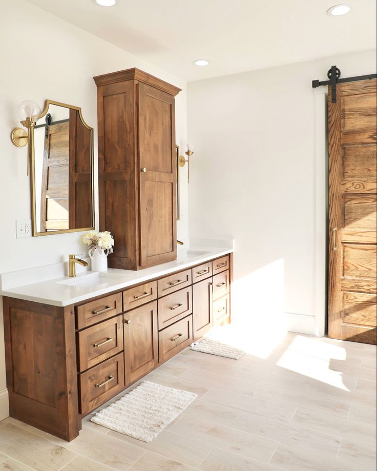 a bathroom with wooden cabinets and marble counter tops, white walls and wood flooring