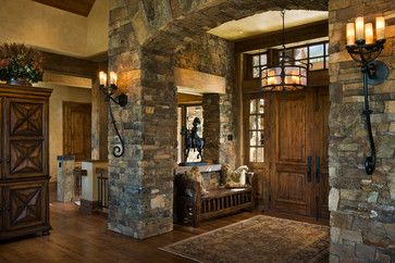 a living room filled with furniture and stone pillars in front of a doorway that leads to another room