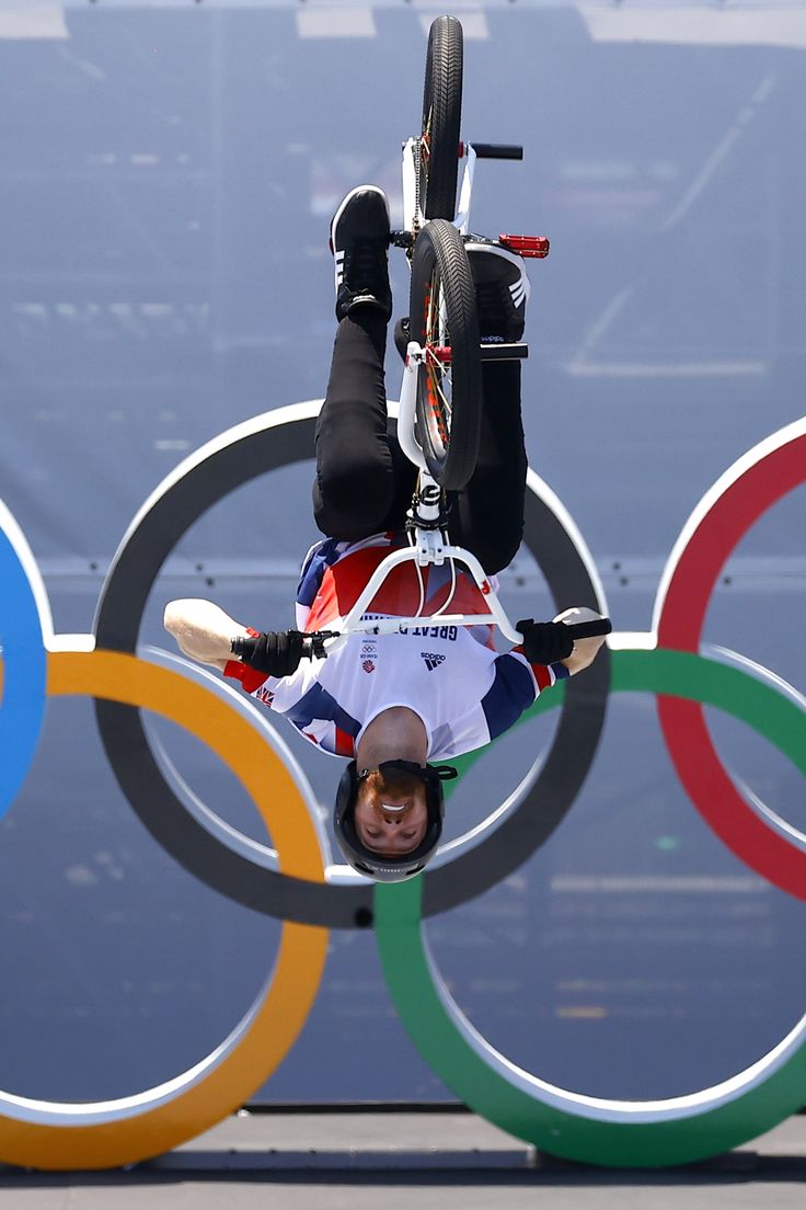 a man is upside down in front of the olympic rings