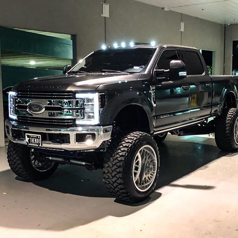 a large black truck parked in a garage next to a building with lights on it's sides