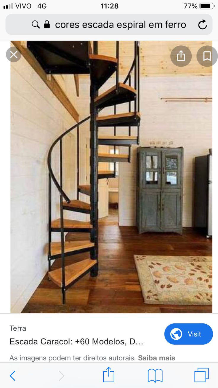 a spiral staircase in the middle of a room with wood floors and white walls, next to a refrigerator