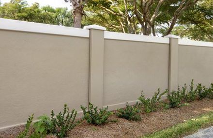 a white fence with green plants growing on the top and bottom, next to a sidewalk