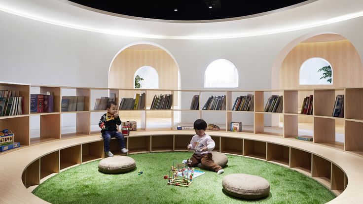 two children are playing in the library with bookshelves and round seating areas on either side