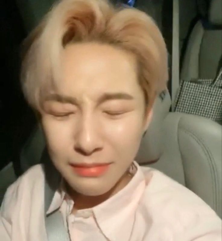 a man with blonde hair wearing a white shirt and silver tie sitting in a car