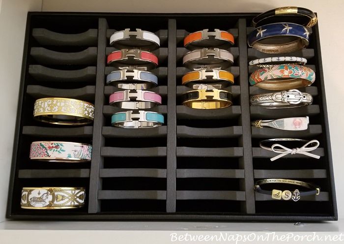 an open drawer with many different types of bracelets in it on top of a table