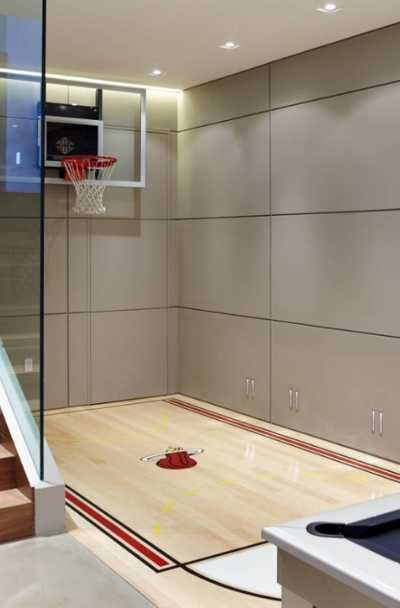 an indoor basketball court in a house with glass walls and stairs leading up to the second floor