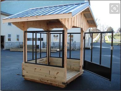 a small wooden shelter sitting in the middle of a parking lot