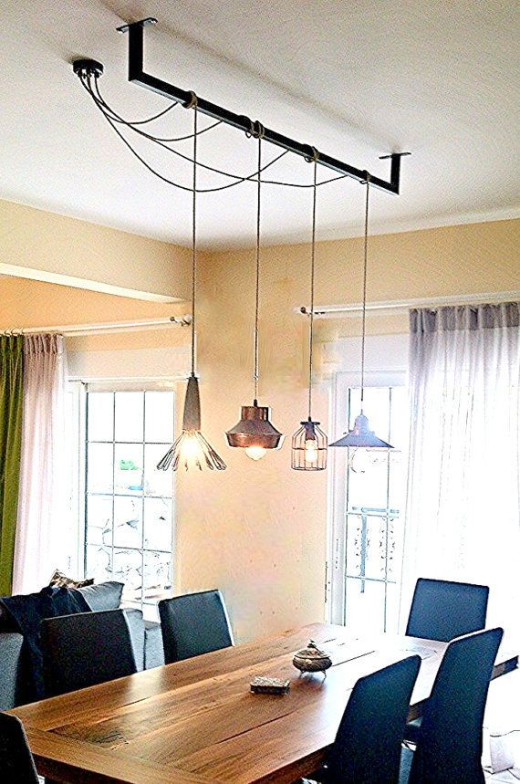 a dining room table with blue chairs and lights hanging from the ceiling