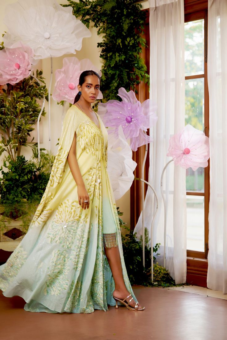 Feel the summer breeze in this flowy Zinnia Kaftan. It is beautifully adorned with floral motif embroidery all over, highlighted with golden and aqua-hued sequence work. To give it that elegant look, an ombre hue of aqua is added at the bottom of the Cape. To match the cape, A fully sequenced dress balances the sophistication and adds a modern touch to the outfit. This summer festive season, this flowy attire with pristine hues is the perfect choice to go with. Cape-style kaftan is covered with Embellished Summer Kurta With Traditional Drape, Designer Floral Print Summer Kurta, Floral Print Kurta For Summer, Designer Floral Print Kurta For Summer, Summer Floral Print Kurta, Summer Wedding Kaftan With Dupatta, Silk Dresses With Floral Embroidery In Traditional Drape, Summer Festive Saree-shaped Kaftan, Floral Print Saree Dress For Summer