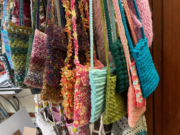 many crocheted purses are hanging from hooks