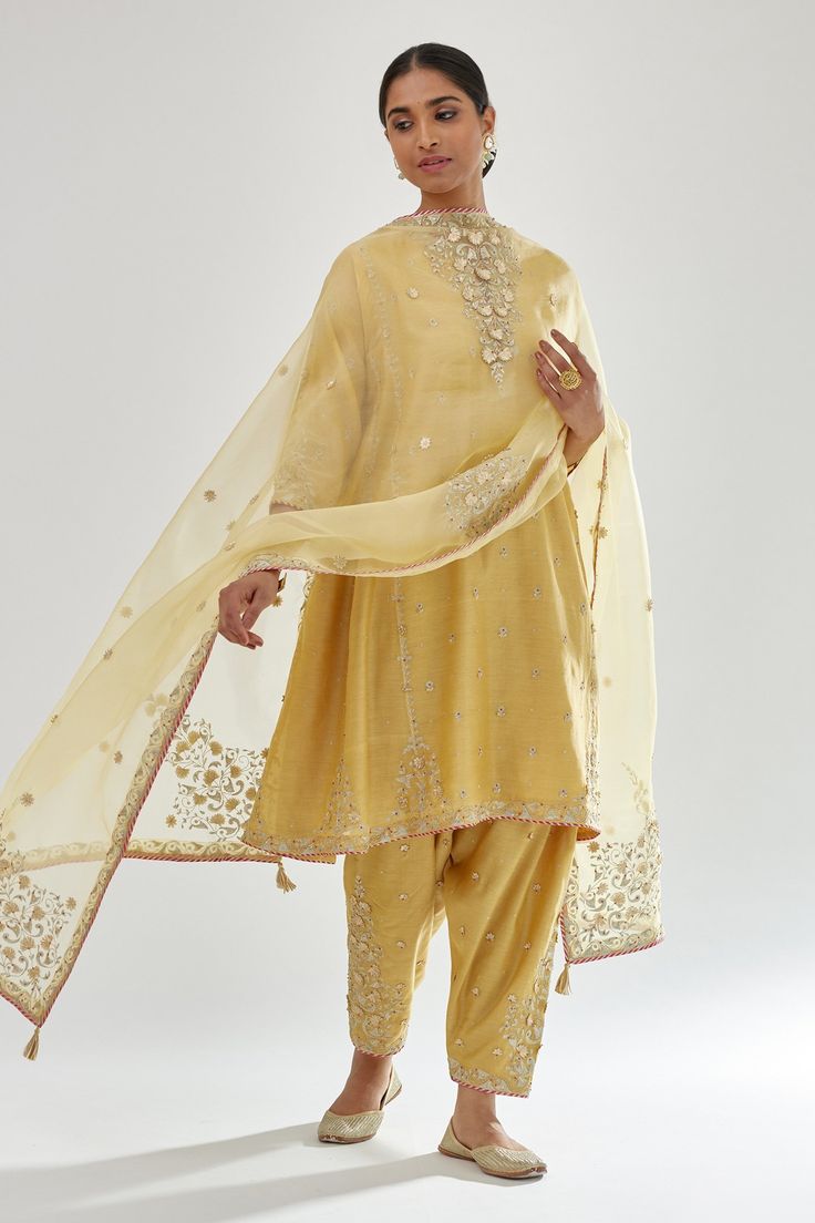 Yellow silk chanderi short kalidar kurta with zari bootis, dori embroidered neckline and contrast bead work. Paired with narrow salwar in dori, zari and gota flower embroidered bootas and dupatta.
Components: 3
Pattern: Embroidery
Type Of Work: Zari, dori, gota, aari, bead
Neckline: Notched
Sleeve Type: Three quarter
Fabric: Kurta and Salwar: Silk Chanderi, Dupatta: Silk Organza
Color: Yellow
Other Details: 
Gota lace embroidered border
Side pockets
Elasticated back
Tassel bordered sheer dupatta Plain Suits, Kurta Embroidery, Sheer Dupatta, Yellow Kurta, Chanderi Dupatta, Red Kurta, Hand Painted Dress, Salwar Designs, Kurti Set