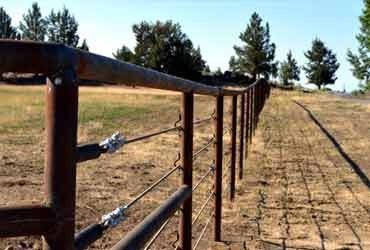 a long fence is in the middle of an open field