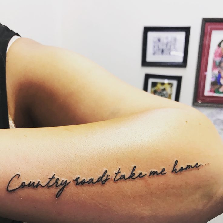 a person with a tattoo on their arm that says, country roads take me home